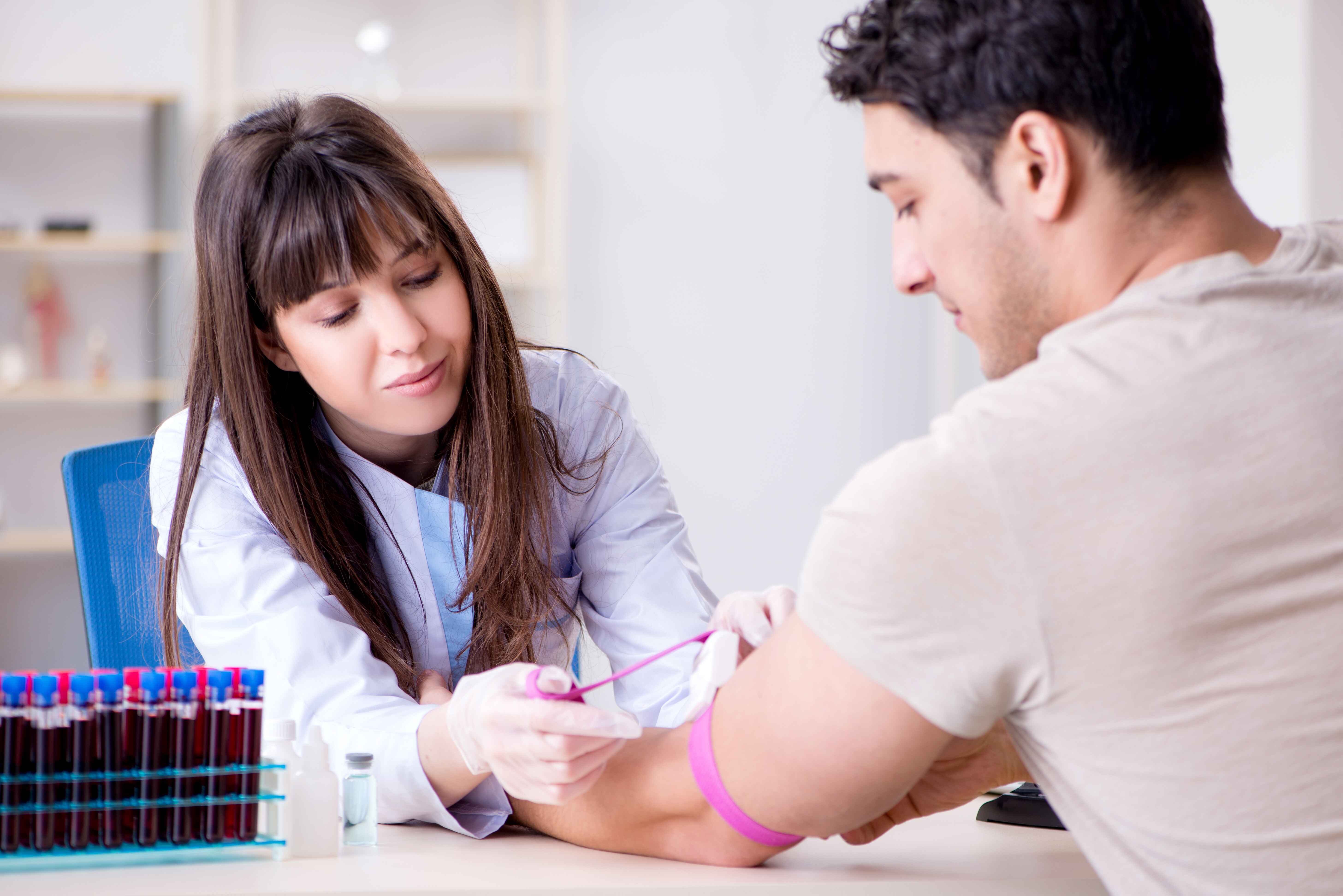 A healthcare worker prepares to draw blood from a patient.