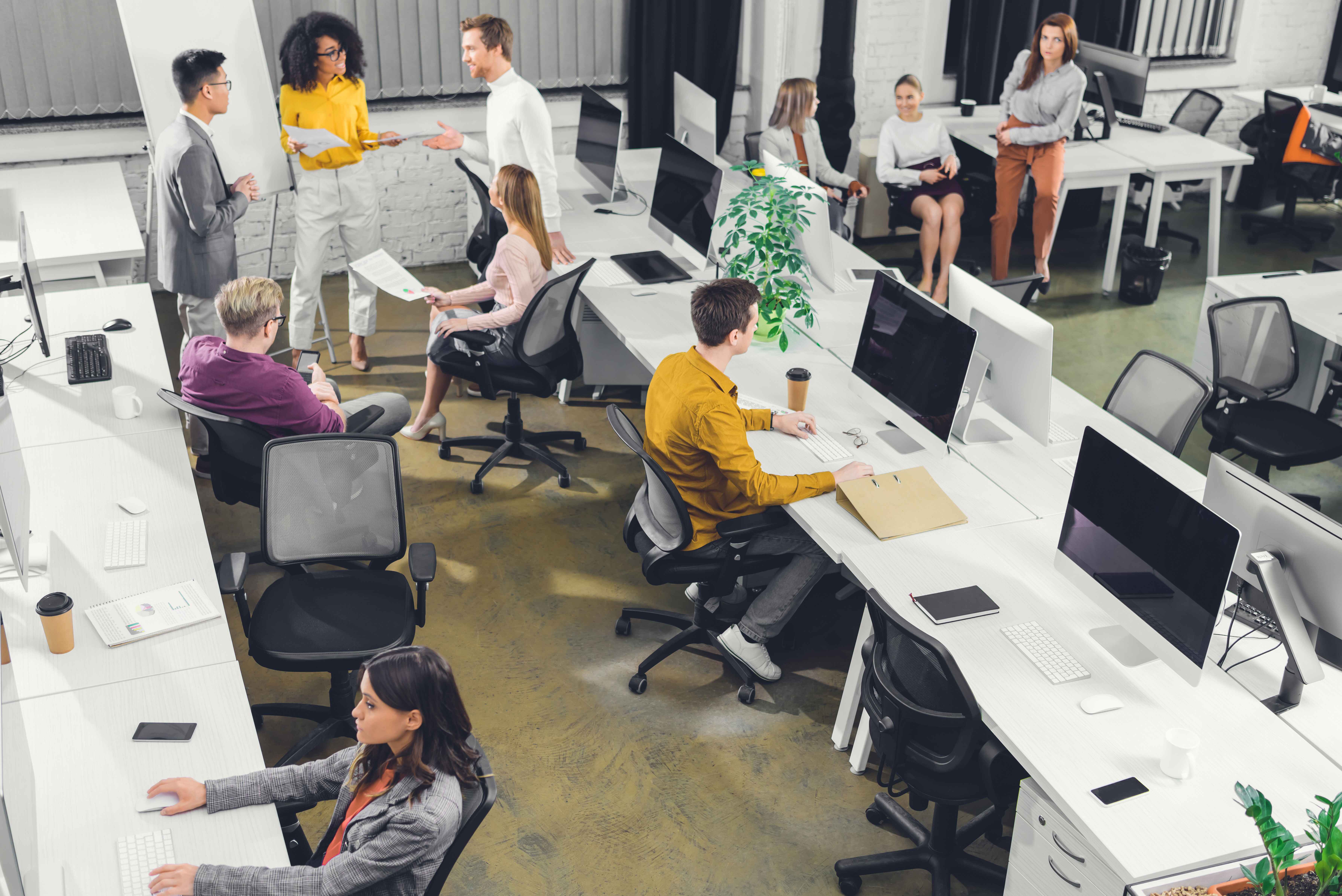 An open-plan office with people working at desks and conversing