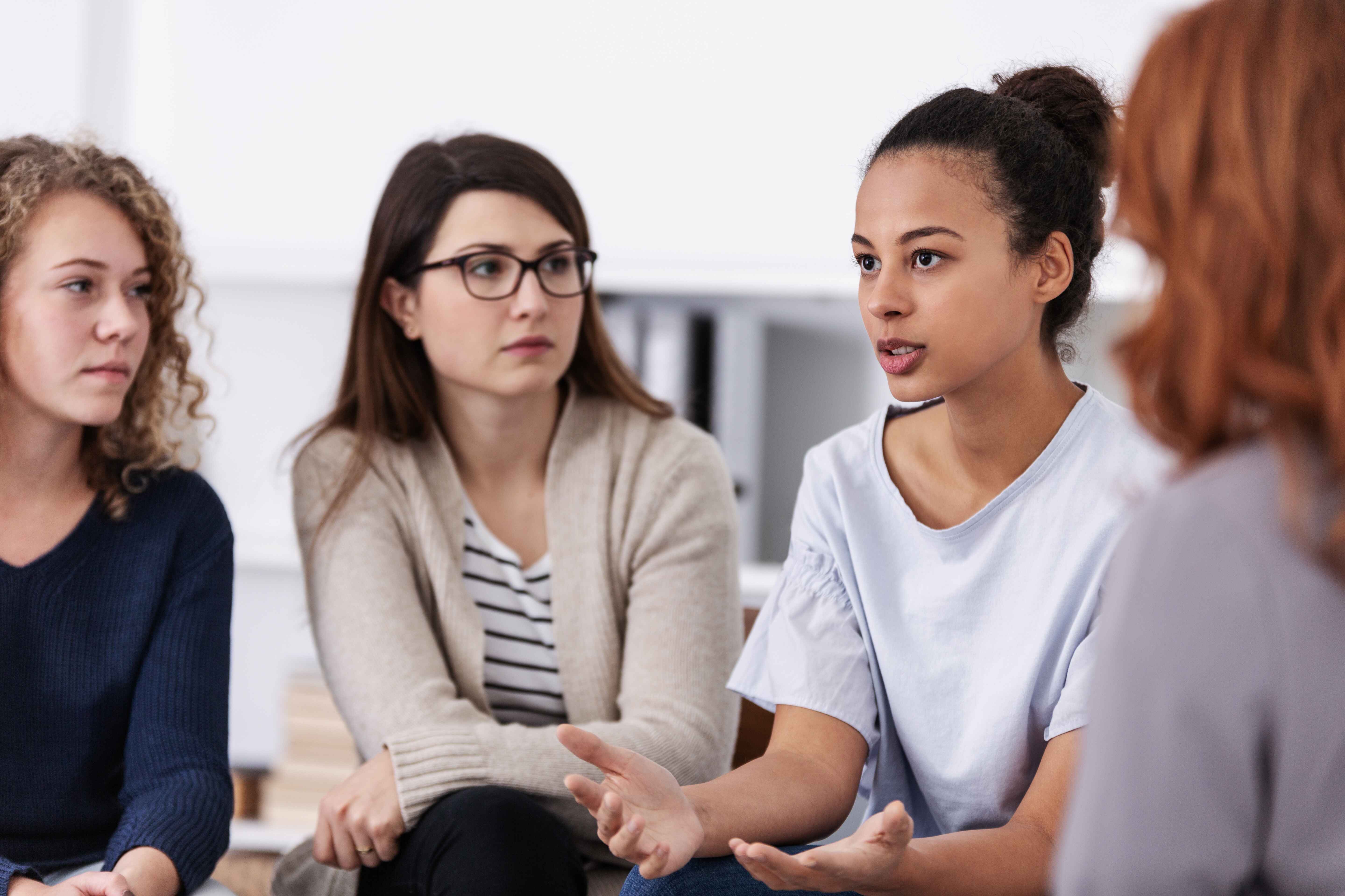 A group of four women in conversation, seated in a semi-circle.