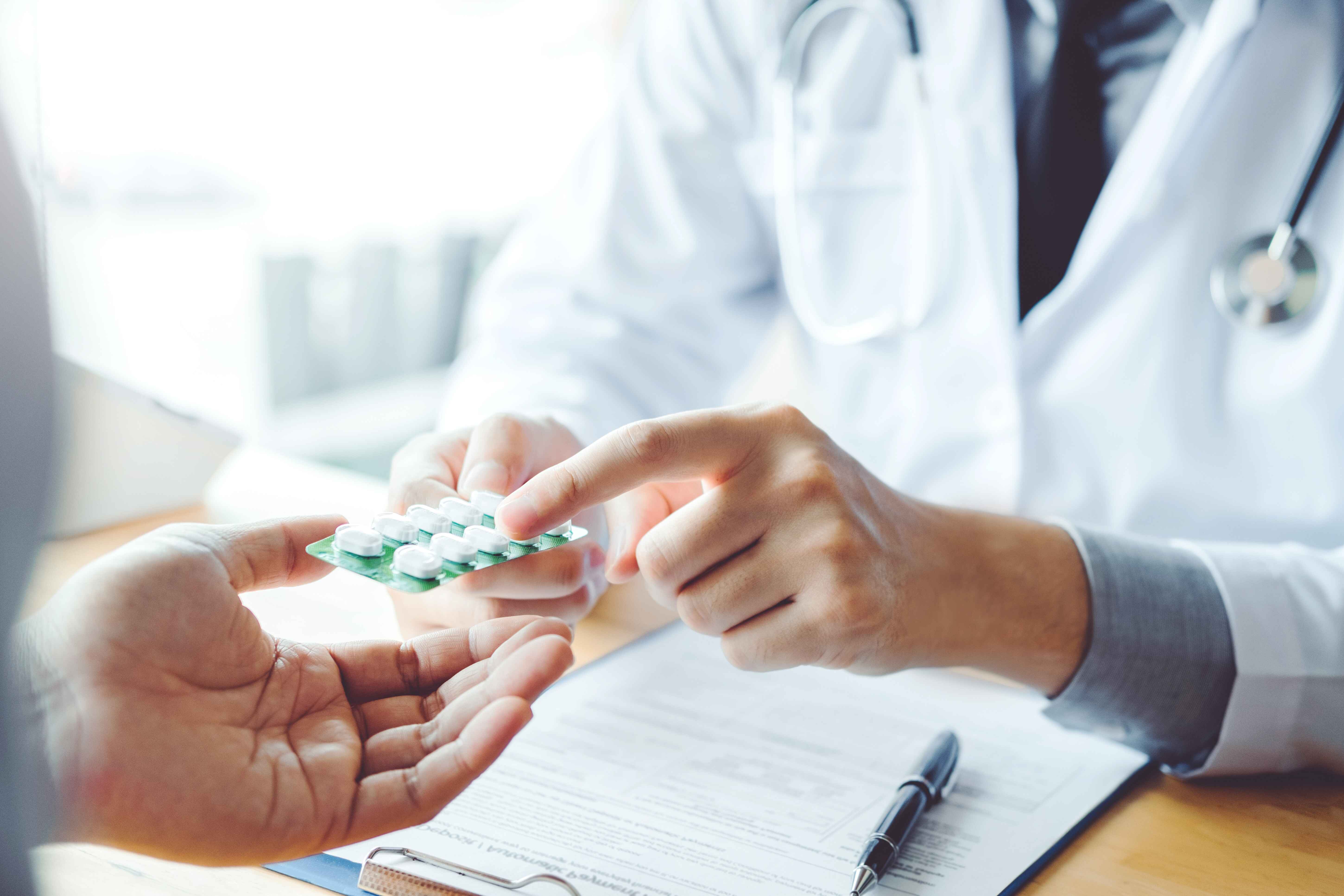 Healthcare professional handing a blister pack of pills to a patient.