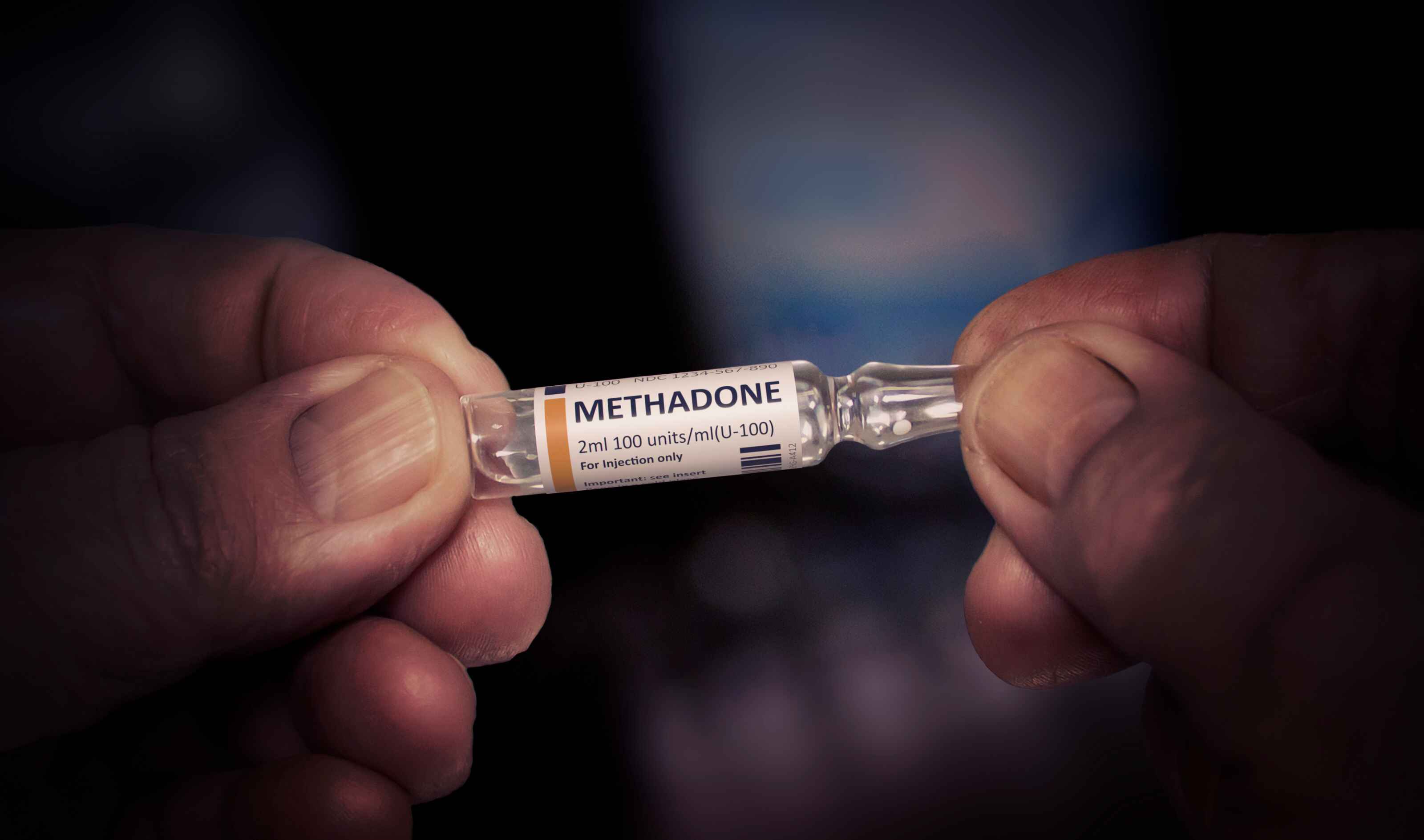 Hands holding a glass vial labeled "METHADONE."