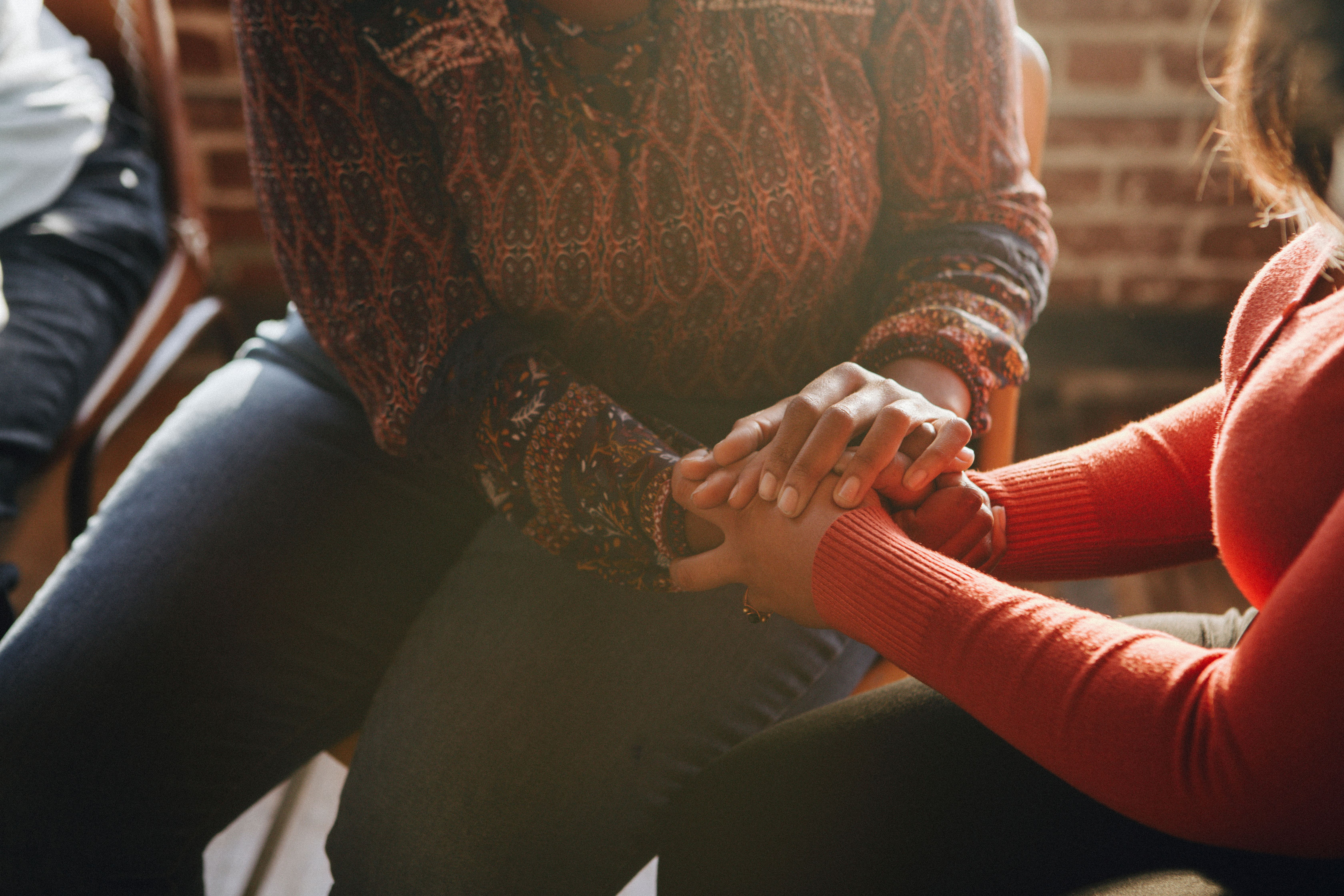 Two people with their faces obscured holding hands