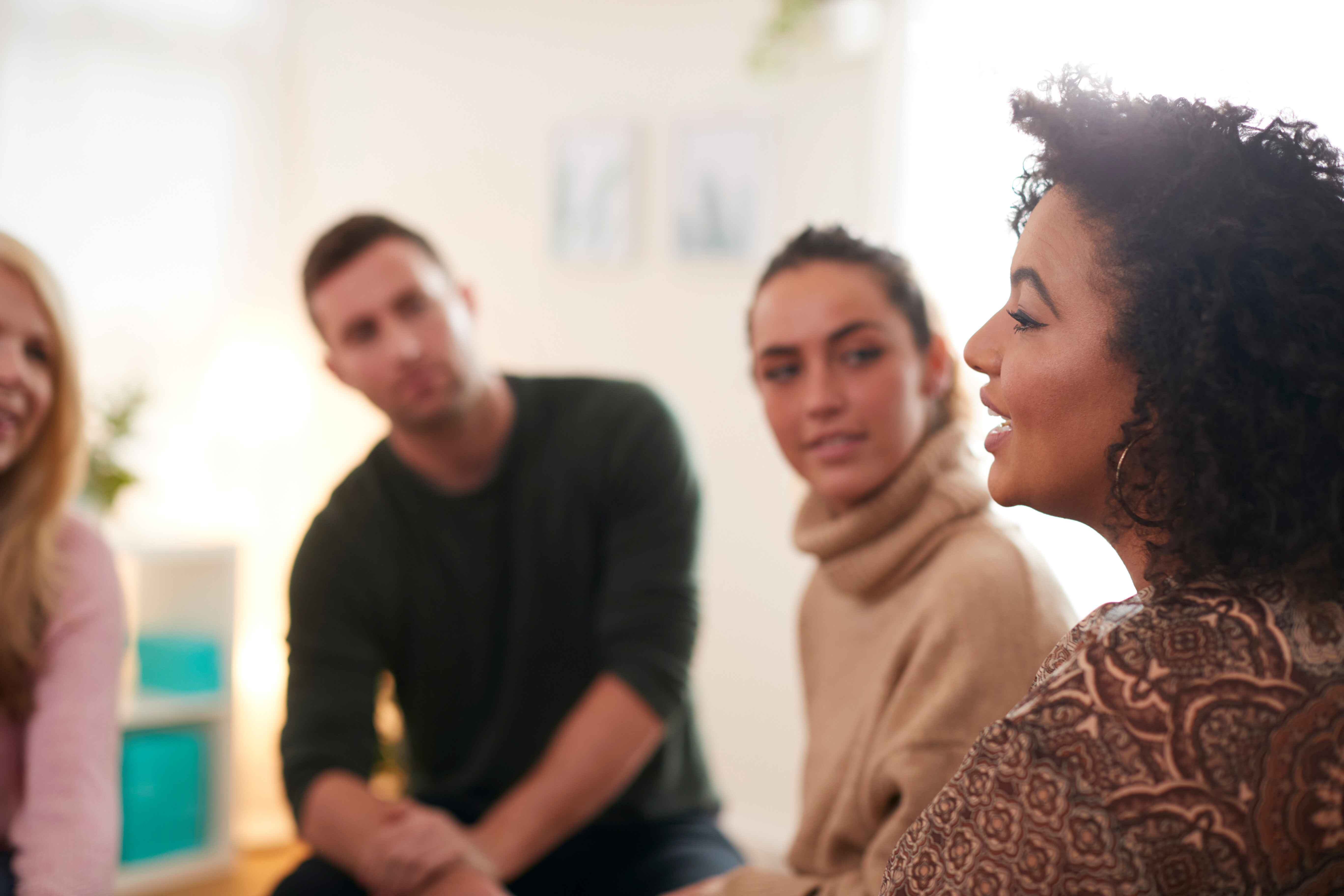 A group of four people engaged in conversation in a casual setting.