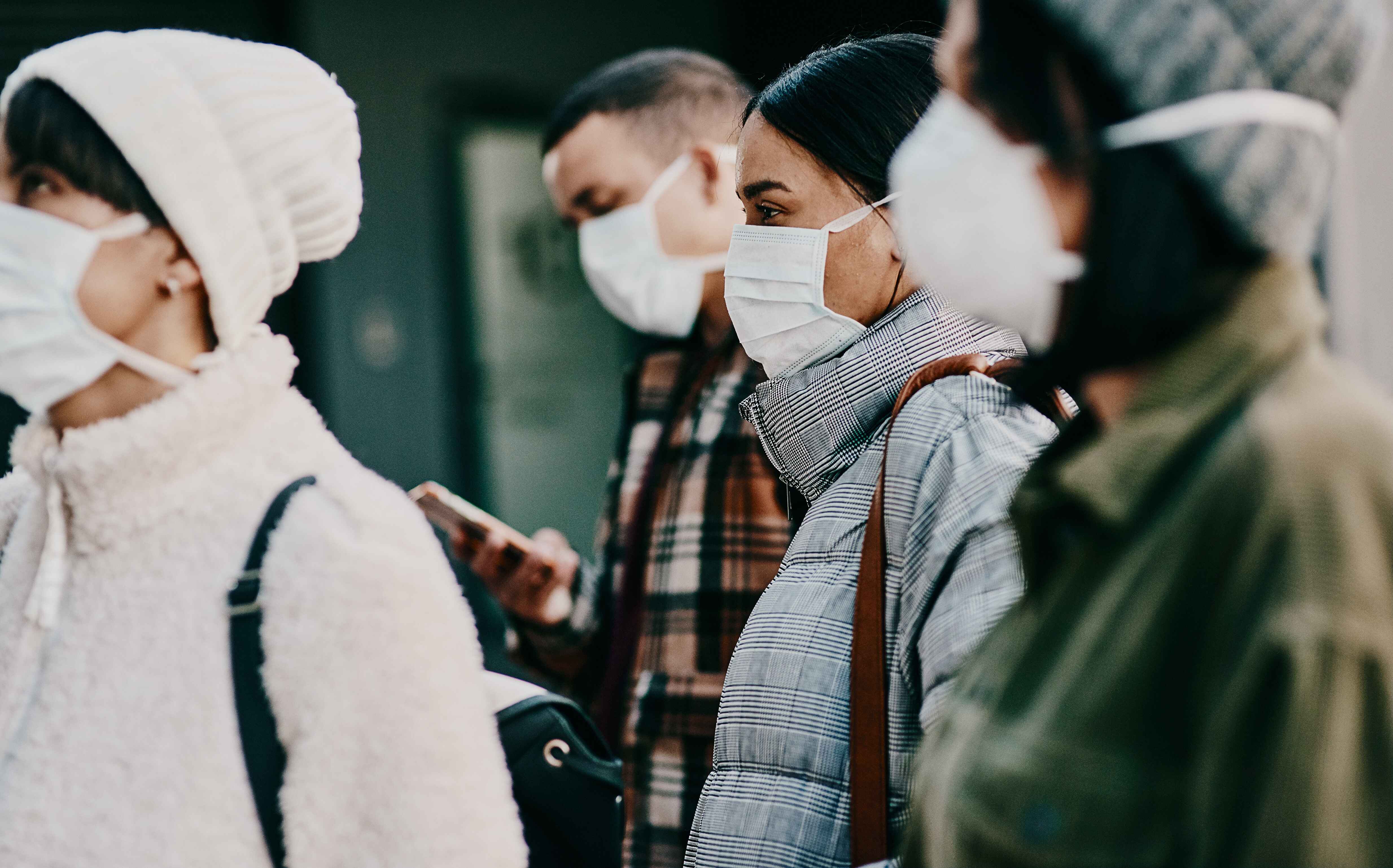 A group of people wearing face masks, standing outdoors.