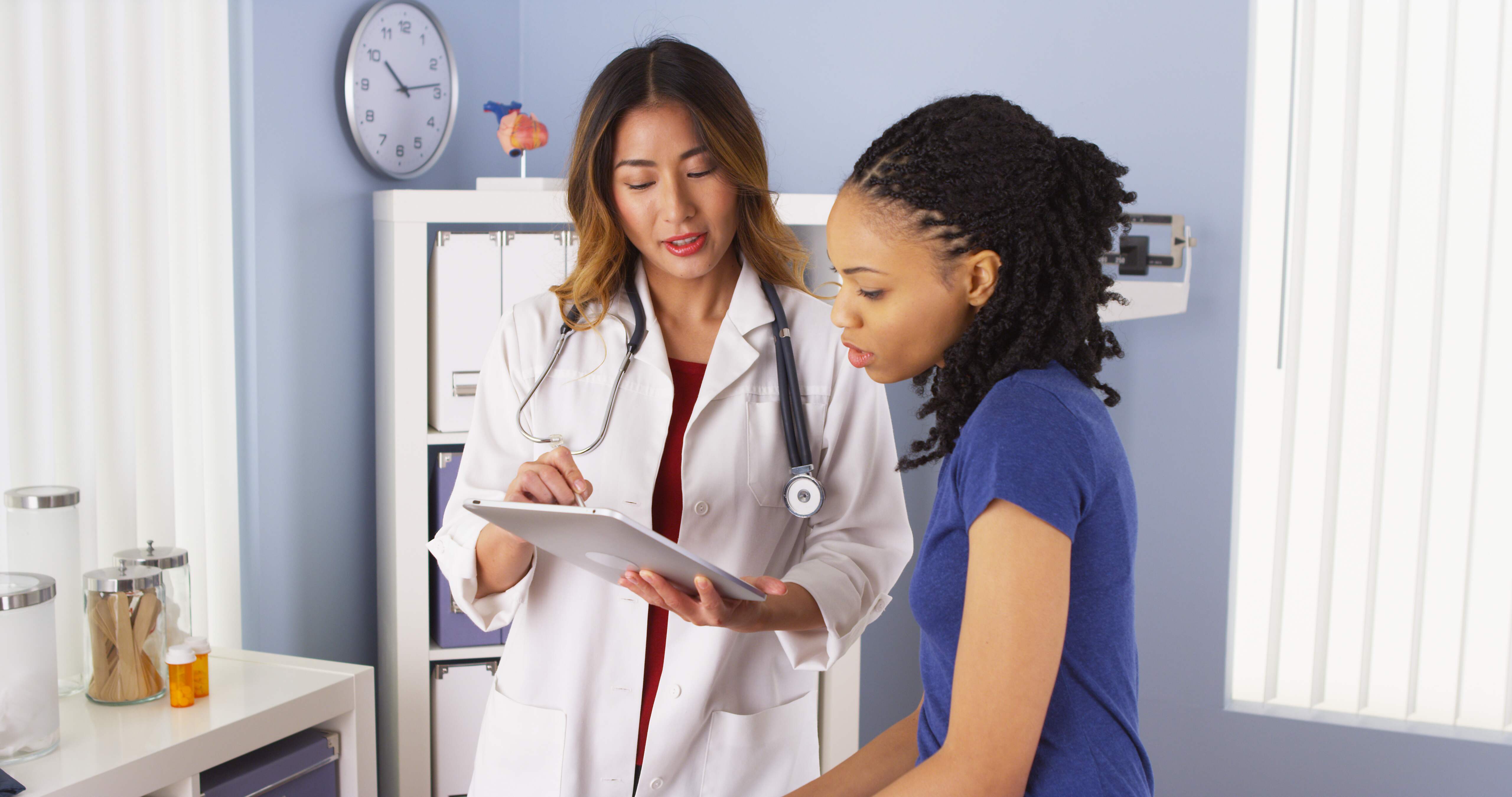 Doctor showing a patient information on a tablet in a medical office.