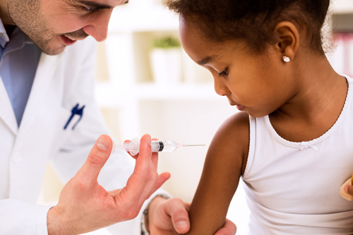 Male doctor gives injection vaccination to young girl