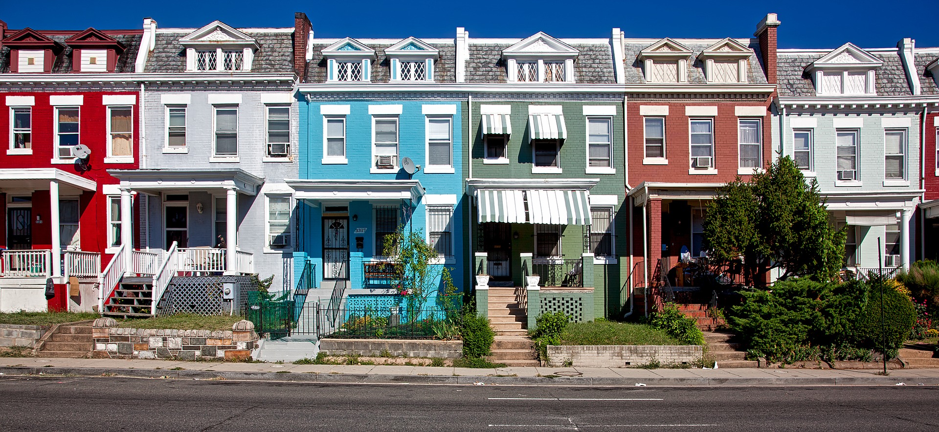 Row of colorful townhouses with similar architectural features.