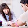 A healthcare worker prepares to draw blood from a patient.