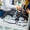 Display of black handguns on a counter with people examining them.