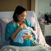 Mother breastfeeding newborn in a hospital bed